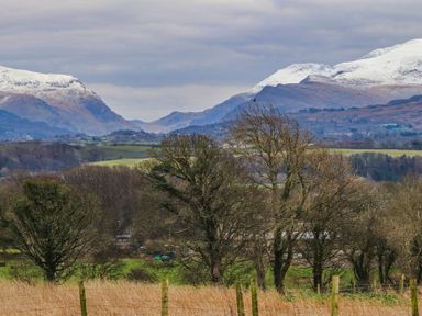 A landscape with bare trees and snow capped mountains in the background at Cae Ffynnon in Star near Gaerwen