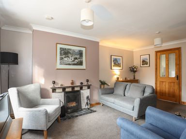 A living room with a fireplace two sofas armchair and framed pictures at Ty Eiddew Ivy House Llanystumdwy near Criccieth