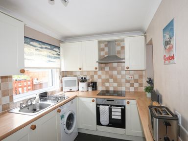 A kitchen with sink washing machine oven toaster and cabinets at Ty Eiddew Ivy House in Llanystumdwy near Criccieth