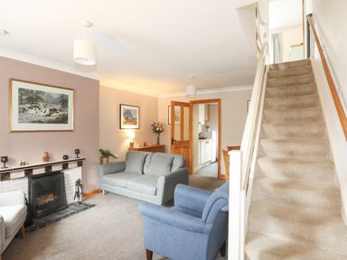A living room with sofas a fireplace and staircase at Ty Eiddew (Ivy House) in Llanystumdwy near Criccieth