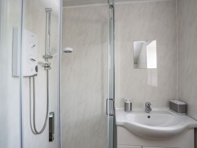 A bathroom with a shower enclosure sink mirror and soap dispenser at Ty Eiddew Ivy House Llanystumdwy near Criccieth