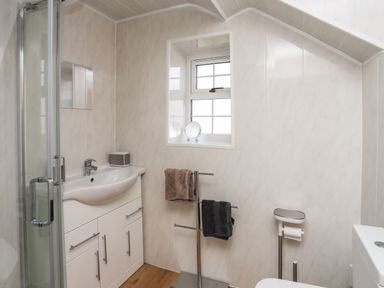A bathroom with a sink cabinet shower towel rack and toilet at Ty Eiddew Ivy House in Llanystumdwy near Criccieth