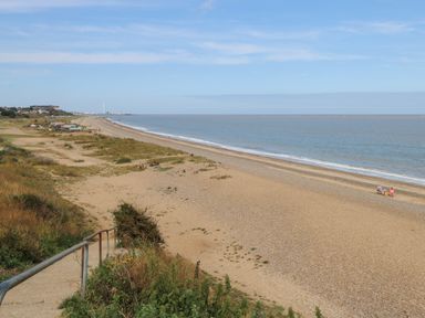 A sandy beach with sparse vegetation and calm sea at Sole Bay Cottage in Lowestoft