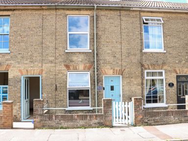 The front exterior of a brick terraced house with light blue doors and windows at Sole Bay Cottage in Lowestoft