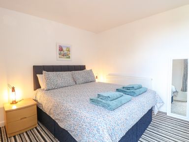 A bedroom with a double bed and folded towels on the bed at Sole Bay Cottage in Lowestoft