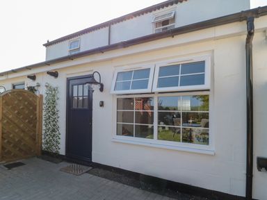 Outside view of a white building with a black door and two windows at 9 Station Cottages in Belford
