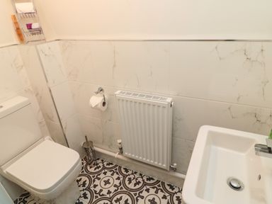 A bathroom with a toilet a sink a radiator and patterned floor tiles at 9 Station Cottages in Belford