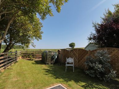 A garden area with green grass white chair wooden fences and shrubs at 9 Station Cottages in Belford