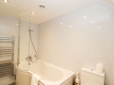 A bathroom with a bathtub shower combination a towel rail and a toilet at Barton Cottage Bourton-On-The-Water