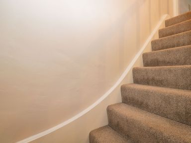 Carpeted staircase with beige walls and a white handrail at Barton Cottage in Bourton-On-The-Water