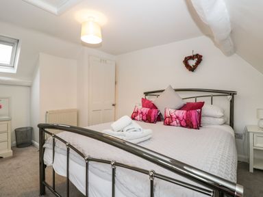A bedroom with a metal bed frame cushions and folded towels on the bed at Barton Cottage in Bourton-On-The-Water