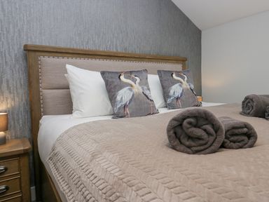 A bedroom with a bed featuring bird print pillows and rolled towels at Crag View Cottage in Stainton with Adgarley near Dalton-In-Furness