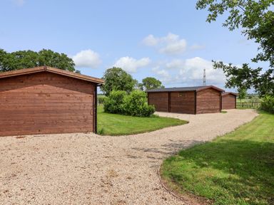 Three wooden lodges with a gravel pathway at Lodge 1 York