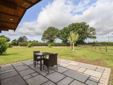A patio with a table and chairs overlooking a grassy area at Lodge 1 in Strensall