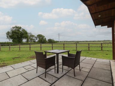 A patio with a table and chairs overlooking a grassy field at Lodge 1 in Strensall