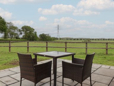 A patio with a table and chairs overlooking a field at Lodge 1 in Strensall