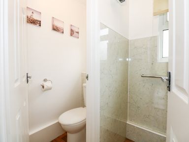 A bathroom with a toilet and a shower area separated by a wall at 8 Royal Chalet Park in Mundesley