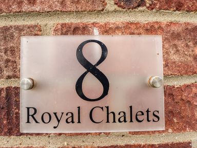 A house number sign with the number 8 and the text Royal Chalets on a brick wall at 8 Royal Chalet Park in Mundesley