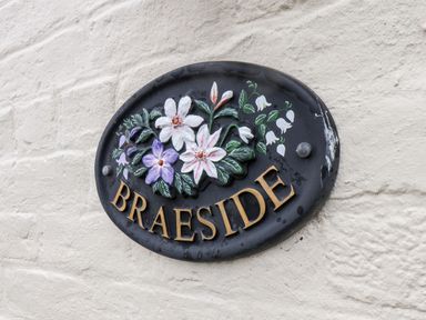 A black oval plaque with flowers and the word Braeside on a textured wall at Braeside in Fylingthorpe