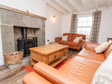 A living room with leather sofas wooden coffee table stone fireplace and basket at Braeside in Fylingthorpe