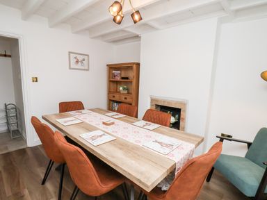 A dining room with a wooden table and six orange chairs at Braeside in Fylingthorpe