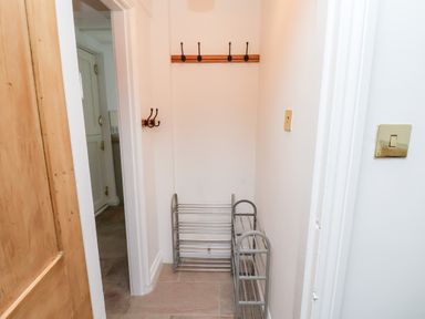 A narrow hall with a wooden door, wall hooks, and metal shoe racks at Braeside in Fylingthorpe