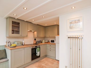A kitchen with cabinets a stove a microwave and a radiator with a framed picture above at Braeside in Fylingthorpe