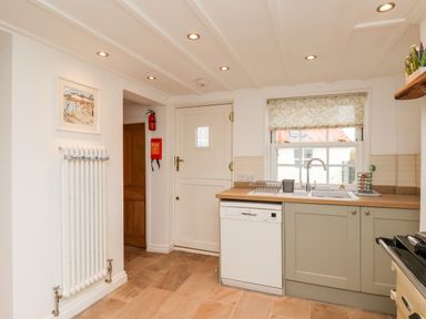 A kitchen with a dishwasher below a counter and a window with a floral blind at Braeside in Fylingthorpe