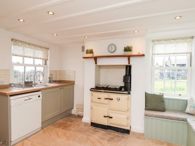 A kitchen with a sink dishwasher stove and window bench seating at Braeside in Fylingthorpe