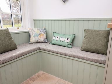 A corner bench with three cushions by a window at Braeside in Fylingthorpe