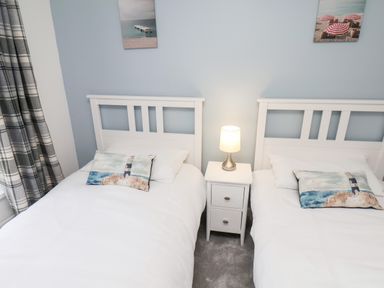 A bedroom with two beds separated by a nightstand with a lamp at Braeside in Fylingthorpe