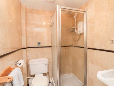 A bathroom with a toilet a towel rack a shower enclosure and a sink at Braeside in Fylingthorpe