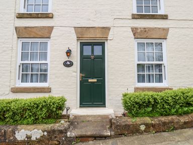 A green front door with two windows on either side and shrubs in front at Braeside in Fylingthorpe