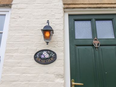 A house exterior with a green door a wall light and a plaque that says Braeside in Fylingthorpe