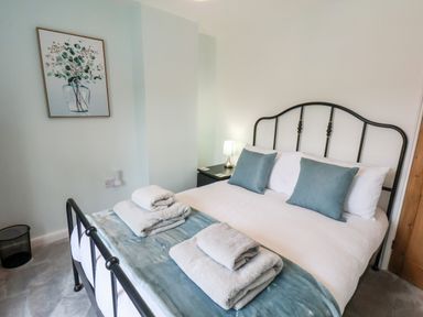 A bedroom with a bed having blue cushions and folded towels and a lamp on a nightstand at Braeside in Fylingthorpe
