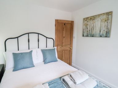 A bedroom with a bed with blue pillows and folded towels at Braeside in Fylingthorpe