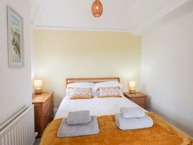 A bedroom with a double bed two bedside tables two lamps folded towels and a framed picture on the wall at Braeside in Fylingthorpe