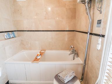 A bathroom with a bathtub a wooden bath tray with a rubber duck towels and a pull chain at Braeside in Fylingthorpe