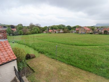 A grassy field with houses and trees in the background at Braeside in Fylingthorpe