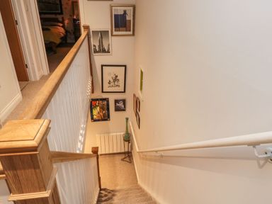 A staircase with handrails and framed pictures on the wall at Lime Court Barn in Sheepwash