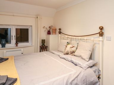 A bedroom with a metal bed frame and pillows including one with a sheep design at Lime Court Barn in Sheepwash