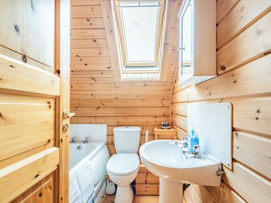 A small bathroom with a bathtub toilet sink and skylight window at Robin Lodge in Llanbedr