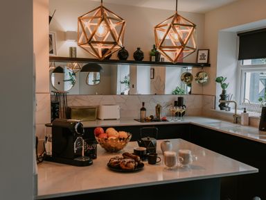 A kitchen with a countertop holding a coffee maker fruit bowl plates with pastries and drinks at 37 Jubilee Street Llandudno