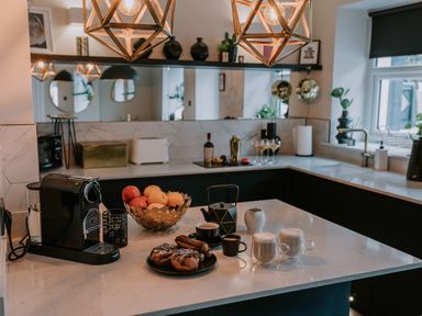 A kitchen with a coffee machine pastries fruit bowl and cups on the countertop at 37 Jubilee Street in Llandudno