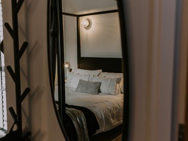 A bedroom with a bed with white bedding and pillows reflected in a mirror at 37 Jubilee Street in Llandudno