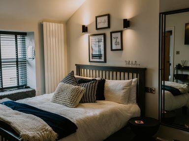 A bedroom with a bed pillows and framed pictures on the wall at 37 Jubilee Street in Llandudno