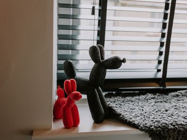 Two balloon dog sculptures one red and one black on a windowsill next to a gray knitted blanket at 37 Jubilee Street in Llandudno