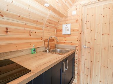 A kitchen with a wooden countertop sink and black cabinets at Cleugh Lodge in Lockerbie