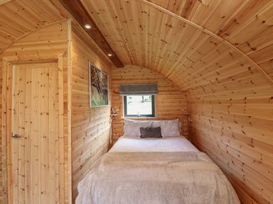 A bedroom with a bed in a wooden cabin at Cleugh Lodge in Lockerbie