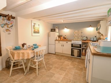 A kitchen with a dining table set with dishes and a refrigerator stove and countertop appliances at Cosy Cottage in Bawdeswell